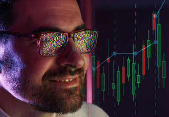 Stock trader or financial analyst working on investment strategy. Data reflecting in man's glasses