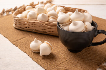 Sweet meringue, a Brazilian sweet called suspiro made with egg whites and sugar, positioned on rustic fabric and accessories, selective focus.