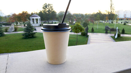disposable cup with a hot drink in hand, in a city park. hot warming drink during autumn blues. warms, gives warmth and lifts the mood. tea, coffee, cappuccino or hot chocolate