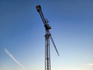 A tower crane stands against a blue sky