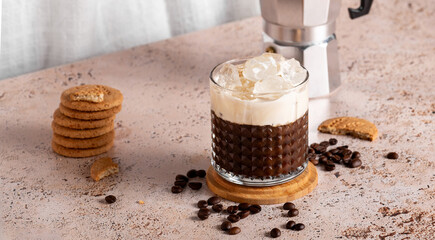 Iced coffee with espresso moka pot and cookies on beige textured countertop, web banner