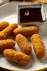 Crunchy, golden snacks are artfully arranged on a plate beside a small bowl of rich dipping sauce, tempting the senses with their crispy texture and savory flavor