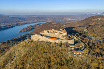 Visegrad, Hungary - Aerial panoramic drone view of the beautiful high castle of Visegrad on a moody autumn sunset. Danube Bend (Dunakanyar) and amazing golden sunset at background.