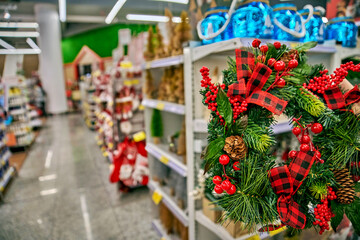 Christmas wreath adorned with red berries and plaid ribbons, displayed in a mall aisle, featuring vibrant decorations and ample blurred copy space for festive messages