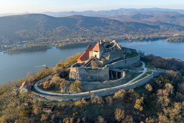 Visegrad, Hungary - Aerial panoramic drone view of the beautiful high castle of Visegrad on a moody autumn sunset. Danube Bend (Dunakanyar) and amazing golden sunset at background.