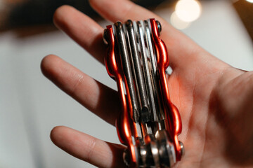 A compact red multitool resting in an open hand, showcasing its metal bits and practical design. Perfect for illustrating concepts of repair, craftsmanship, portability, and everyday utility.