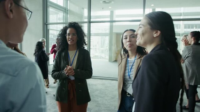 People gathered in a spacious hall, engaging in lively conversation and networking. They are smiling and laughing, creating a friendly and positive atmosphere during a business event or conference.