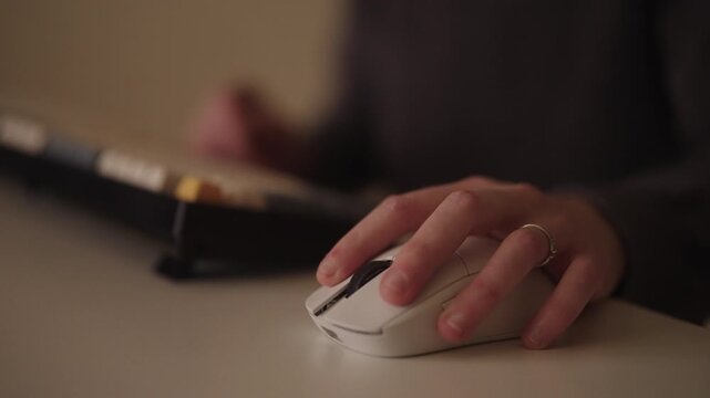 Close-up of female student hands using wireless mouse and then typing on mechanical keyboard while working or studying online sitting at desk at home in dark room. Shooting in slow motion.