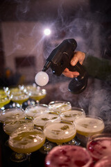 Elegant smoky cocktail, Craft bartenders create visually stunning smoky drinks ambiance, Nightlife scene features misted cocktails with dramatic lighting and sensory effects