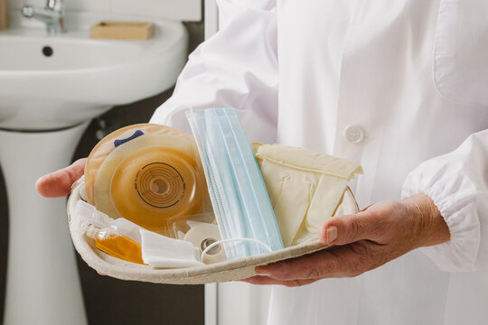 A nurse holds a tray with a colostomy bag and medications.