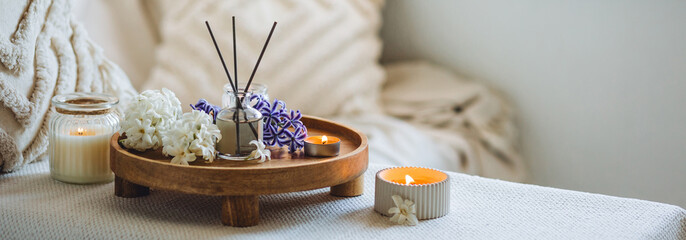 Banner. Home comfort, coziness, aromatherapy. Cozy interior with knitting, burning candles and aroma perfume diffuser in the living room. Fresh spring blossom fragrance, white hyacinth