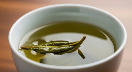 Close-up of fresh green tea with leaf in white cup on wooden table