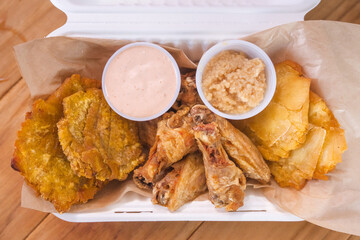 Fried tostones served with mayo ketchup and garlic dipping sauce in a paper tray