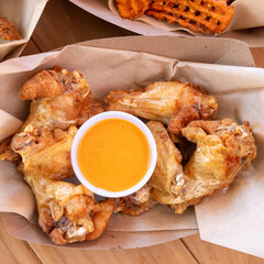 Fried chicken pieces with orange dipping sauce in a paper tray