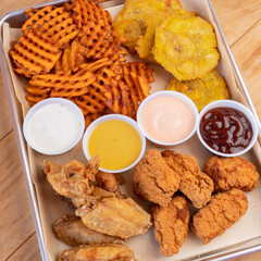 Tray of fried chicken tenders, waffle fries and plantain chips with assorted dipping sauces