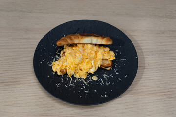 A plate of croissant with scrambled eggs with cheese.