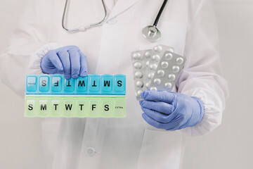An elderly woman holds pills and an organizer in her hands.