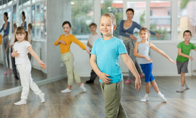 Naklejka premium Boy with friends repeat teaches sequences of movements during training, train to perform electro dance, enjoys active hobby to her favorite music. Unrecognizable female teacher administer conduct