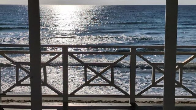 Des vagues bleu fonc&eacute; aux reflets m&eacute;talliques d&eacute;ferlent lentement vers le rivage sablonneux, laissant derri&egrave;re elles un sillage d'&eacute;cume.