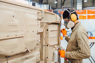 Specialist spraying anti rust sealant into the hidden chassis cavities. Protection against corrosion and internal body element sealing in a professional auto service shop