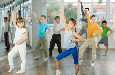 Obraz premium Children training modern dance moves together in studio under the guidance of a teacher