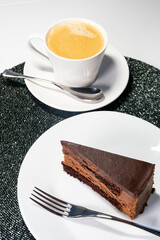 Chocolate mousse cake on plate in festive fashion style. Stylish dessert with sparkling detail and coffee. Indulgent treat
