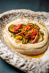 Creamy hummus topped with pickles and chili