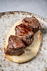 Juicy grilled beef cubes on flatbread closeup