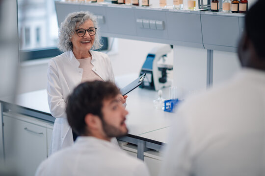 Senior scientist mentoring young students in a lab