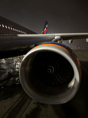 Russia, St.Petersburg, the plane is standing on the airport runway at night, many passengers are walking down the ramp to board the plane, a huge turbine on the wing of the aircraft