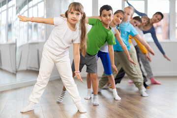 Happy smiling preteen dancers practicing dance routine with female choreographer in modern studio
