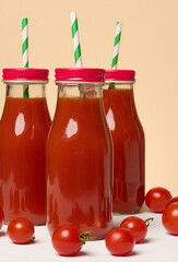 Glass bottles with tomato juice with red caps. Fresh red tomatoes