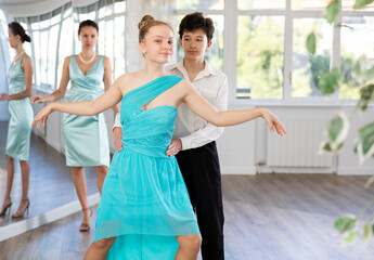 Obraz premium Dance teacher teaches a girl and boy couples ballroom dancing