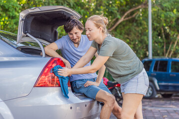Woman and man washing a car together outdoors, working as a team to clean the vehicle and enjoy a productive moment. Household chores, teamwork and everyday lifestyle concept, showing cooperation