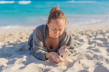 Woman enjoying peaceful time at the beach, relaxing on the sand with ocean views and warm sunlight. Summer leisure, wellbeing and travel concept, representing freedom, calmness and mindful coastal