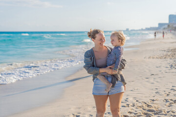 Woman spending quality time with her son on a sunny beach, enjoying the warmth, waves and playful bonding moments. Summertime leisure, family connection and coastal relaxation concept, representing