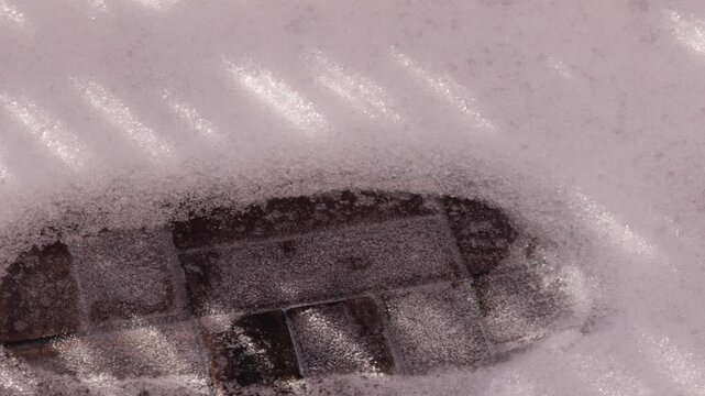 Icy snow-covered footprint on brick surface in winter lighting