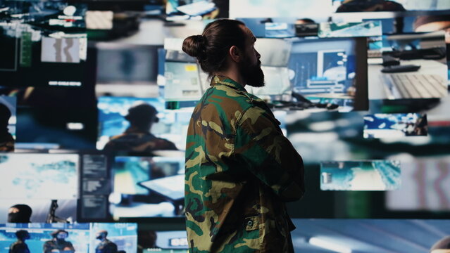 Young soldier working in command center with satellite surveillance integrating data, intelligence and AI warfare tactics for war planning in a national defense mission. Armed forces. Camera B.