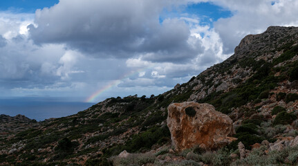 Rocky Coastal Hillside With Rainbow Over the Sea