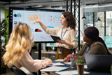 Diverse women professionals focus on report writing and analytics in a meeting, showcasing empowerment through goals and determination for success in a competitive work environment.