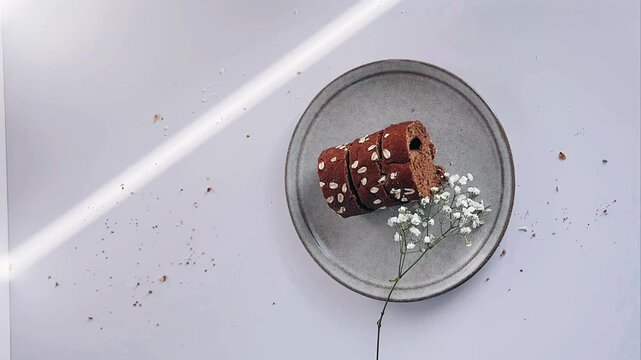 Minimal flat lay of seeded bread slices on a ceramic plate with delicate baby&rsquo;s breath in soft natural light.