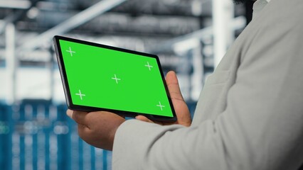 Data center IT expert uses mockup tablet, reviewing performance dashboards of equipment rigs. Server room manager overseeing systems, examining infrastructure on chroma key device, camera B closeup