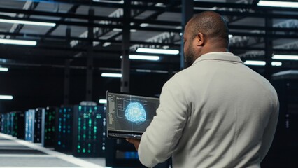 Technician using laptop in data center, managing server virtualization, running scripts. IT expert using programming language on notebook in server hub, finetuning network protocols, camera B