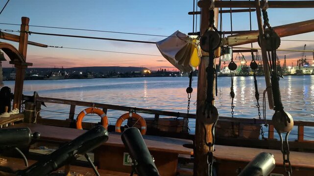 Coucher de soleil sur le port. Une l&eacute;g&egrave;re brise fait doucement tanguer le voilier amarr&eacute;.