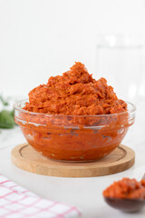 Bowl of homemade ajvar (roasted red pepper dip) with white background. Copy space. Close-up.