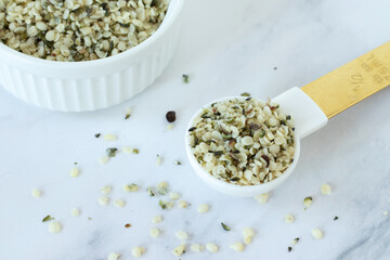 Hemp seeds in spoon on white kitchen table. Close-up.