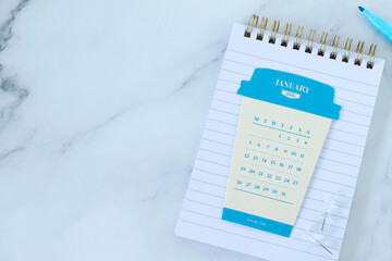 January 2026 calendar on paper coffee cup with notebook. Top view. Copy space. Monthly planning, business goals, weekly organizer concept.