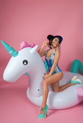 Playful Woman on Inflatable Unicorn in Pink Studio