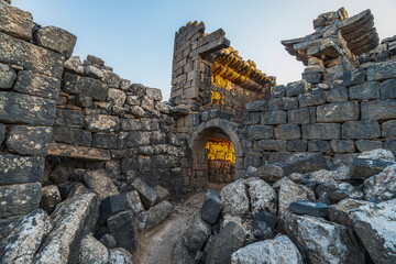 Umm Al-Jimal Sunset: Golden hour on the ancient black basalt ruins in Mafraq, Jordan. Roman tower contrasts with modern cell towers.