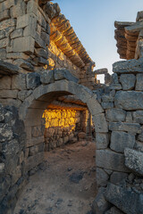 Umm Al-Jimal Sunset: Golden hour on the ancient black basalt ruins in Mafraq, Jordan. Roman tower contrasts with modern cell towers.